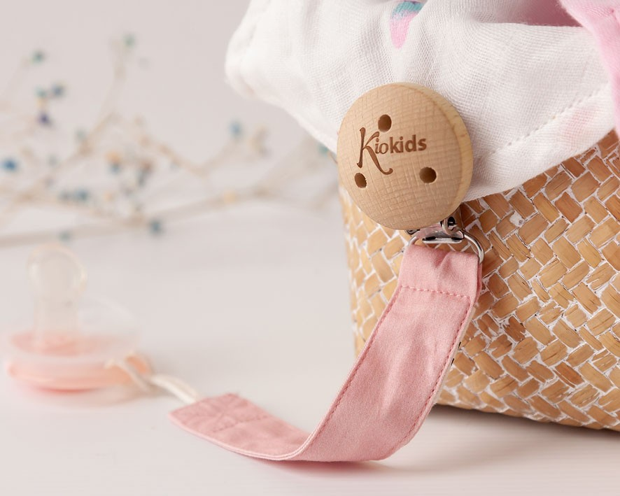 Prendedor de chupeta com botão de madeira 'Kiokids' junto a cesta trançada