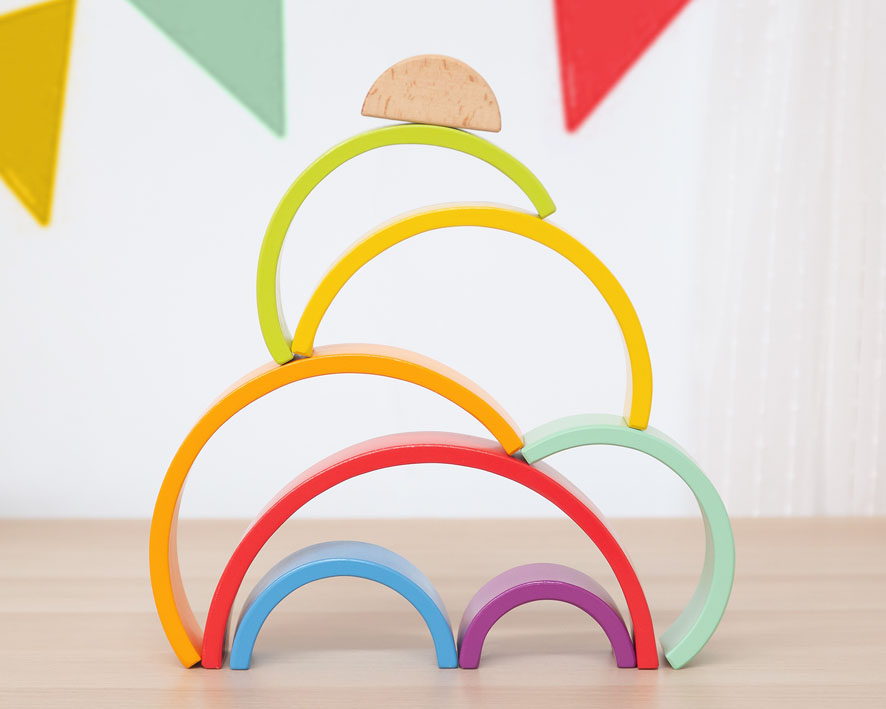 Conjunto de arcos de madeira coloridos empilhados sobre mesa clara.