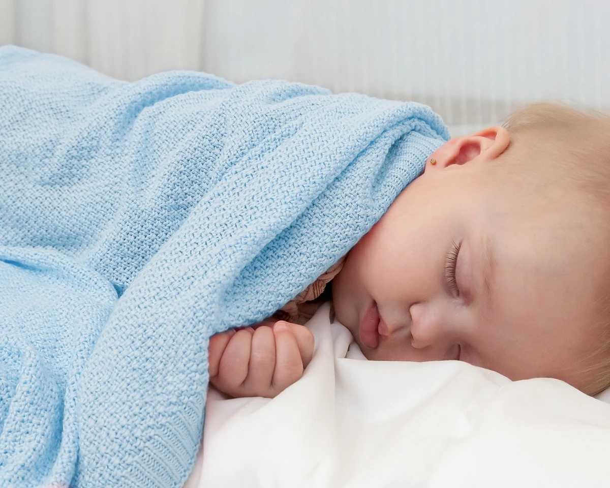 bebé adormecido coberto com uma manta azul clara