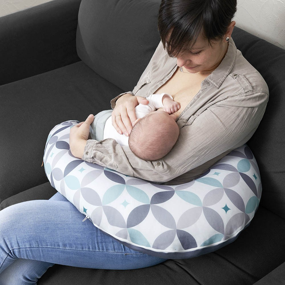 Almofada de amamentação com padrão geométrico colorido usada no colo
