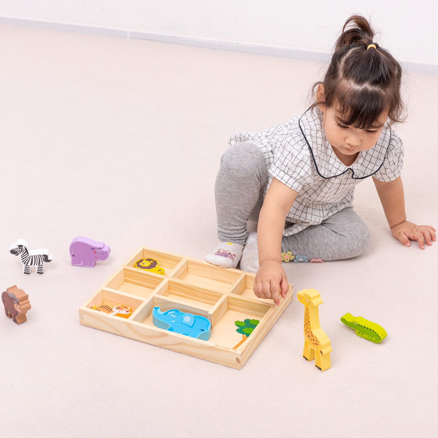 Criança a brincar com brinquedos de madeira de animais coloridos e tabuleiro maçã de madeira