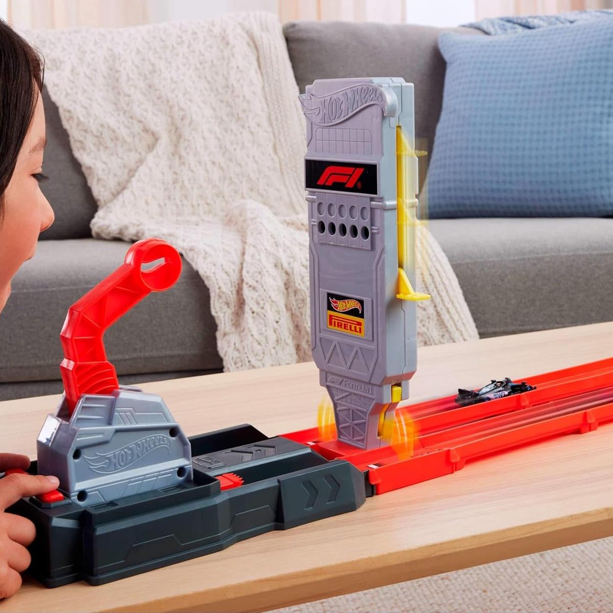 Brinquedo Hot Wheels pista de corrida com lançador vermelho e cinzento e sinal com logos F1 e PIRELLI