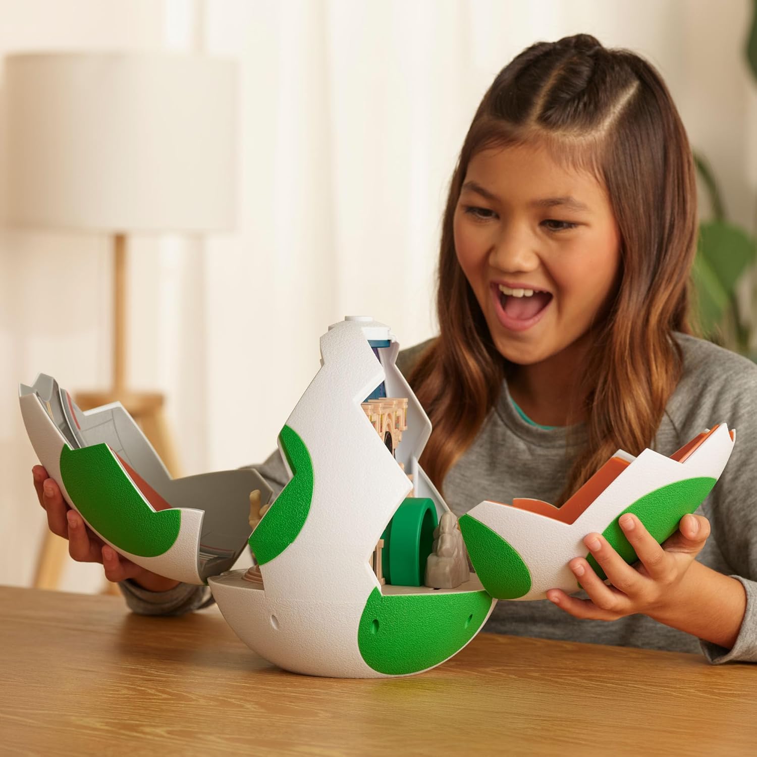 Menina a brincar com brinquedo de esfera branca e verde aberto na mesa