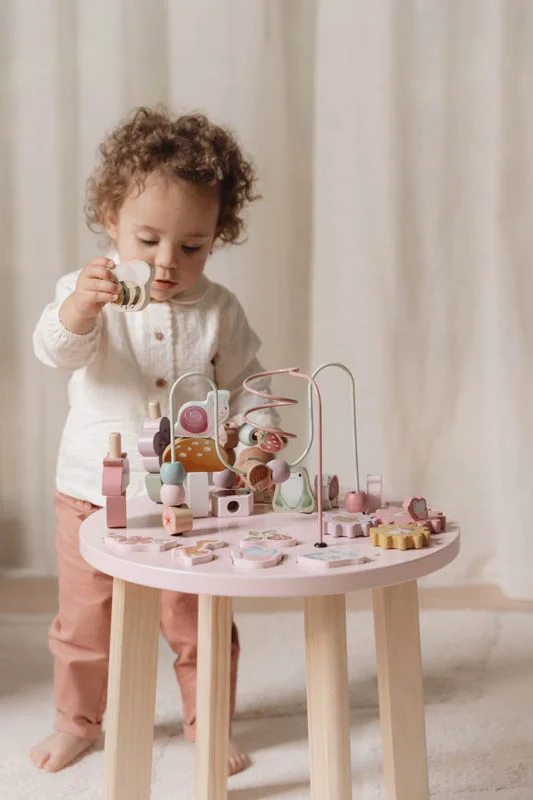 Criança a brincar com mesa de actividades de madeira e ferro