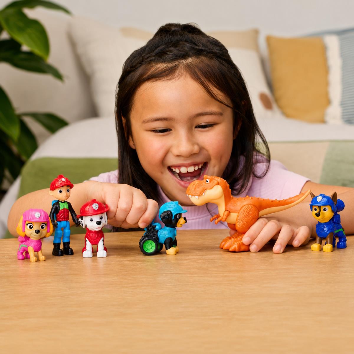 Criança a brincar com figuras de ação coloridas e dinossauro na mesa