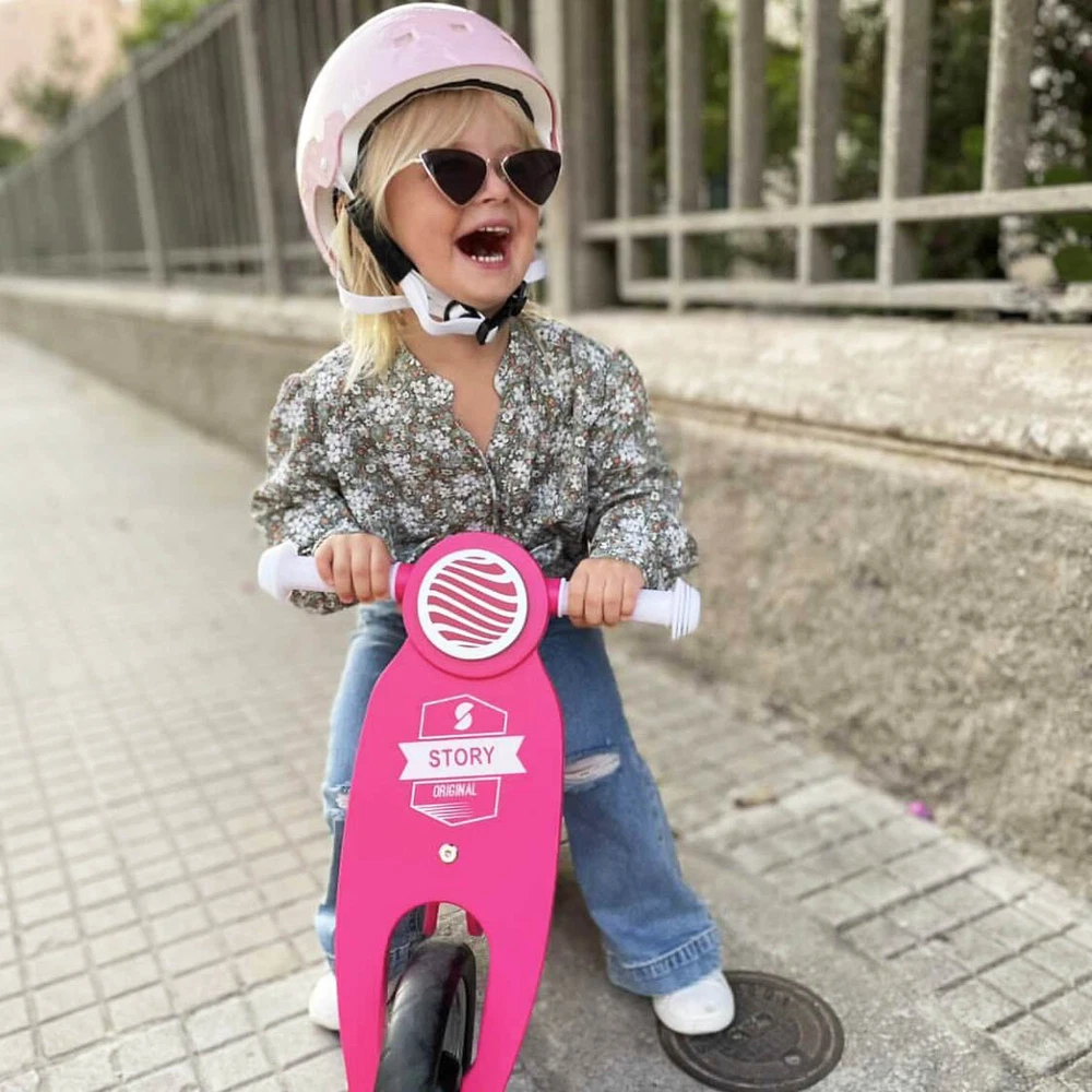 Criança com capacete rosa numa bicicleta rosa num passeio urbano