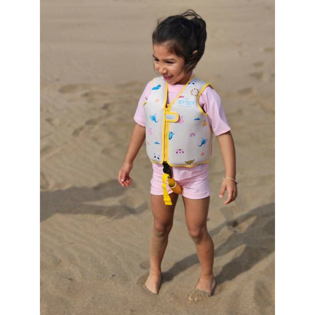 Criança na praia com colete salva-vidas infantil branco com bordas amarelas e estampado colorido