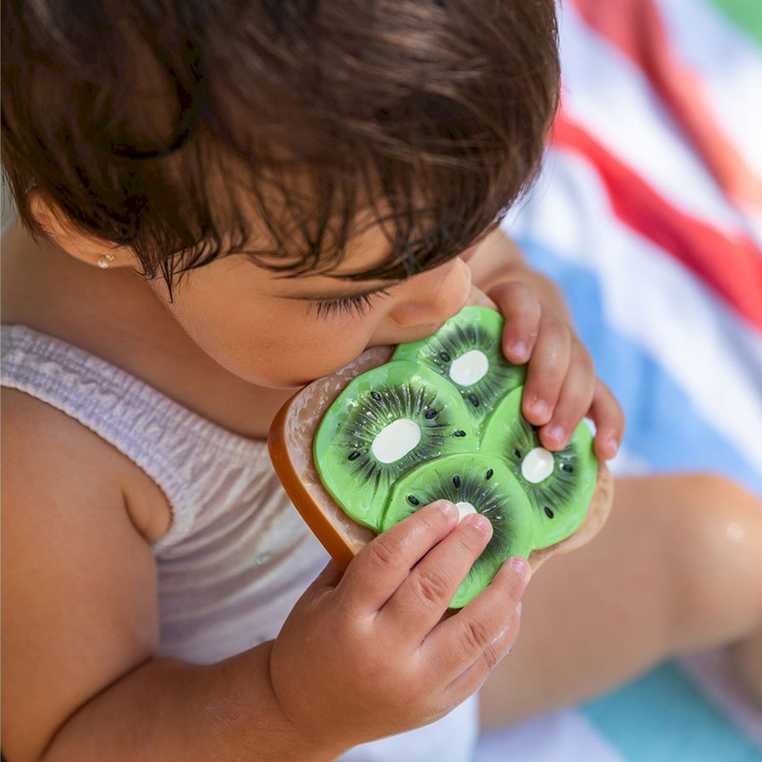 Criança morde brinquedo de silicone em forma de fatias de kiwi verde