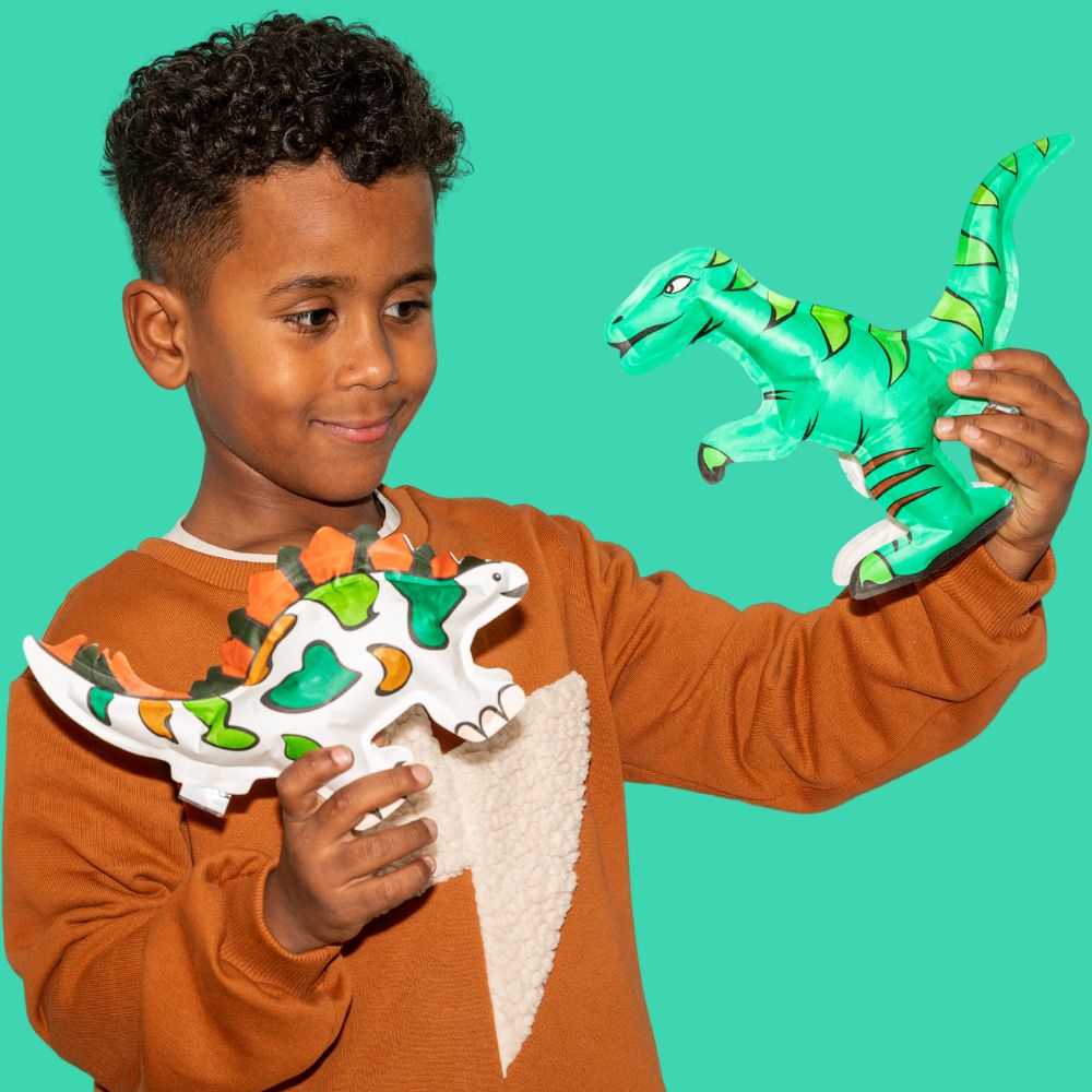 Menino com dois dinossauros de peluche coloridos