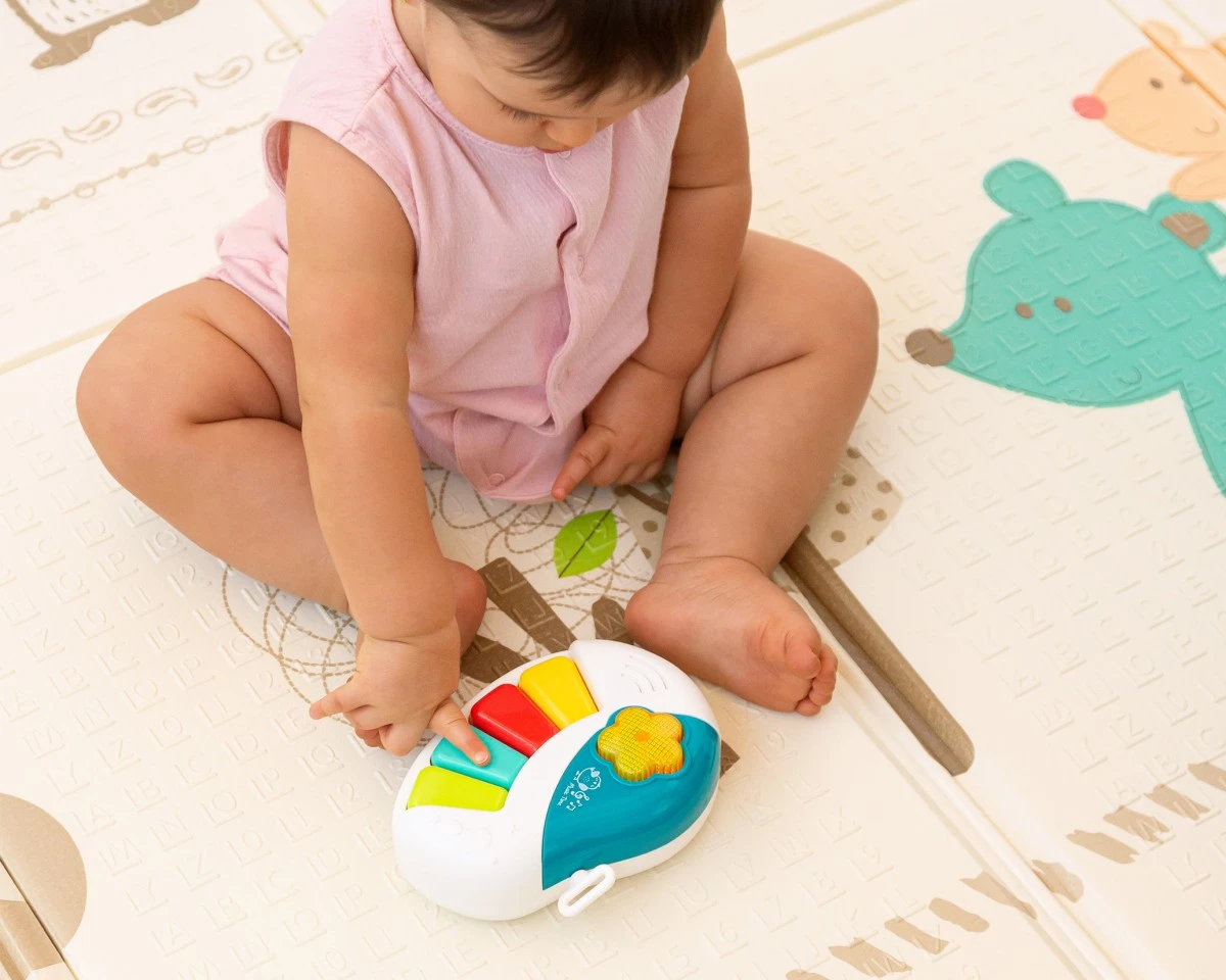 Bebé sentado no chão a tocar brinquedo musical colorido.