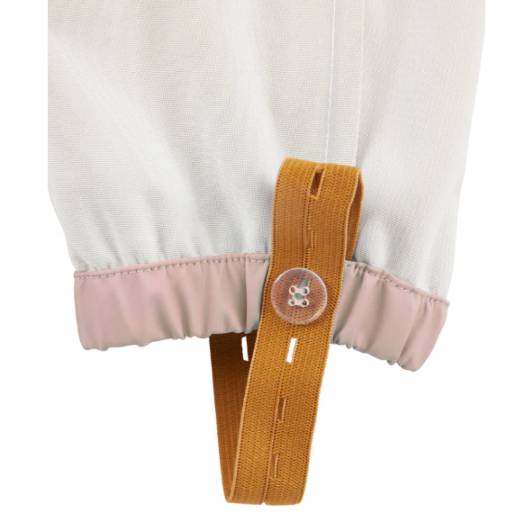 Punho de peça de roupa com tecido branco, elástico rosa claro e tira castanha com botão transparente