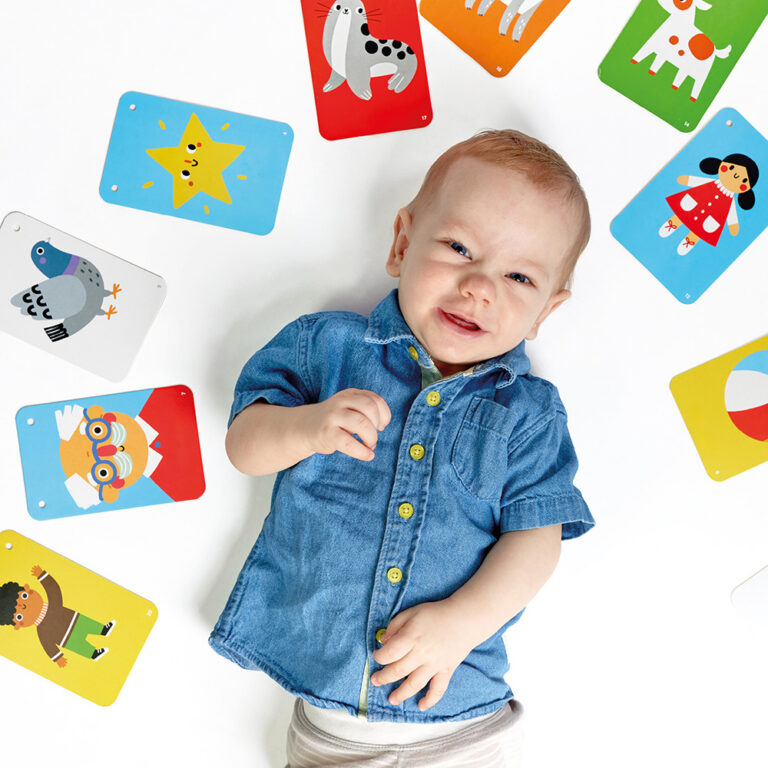 Bebé deitado com camisa de ganga e cartões coloridos ao redor