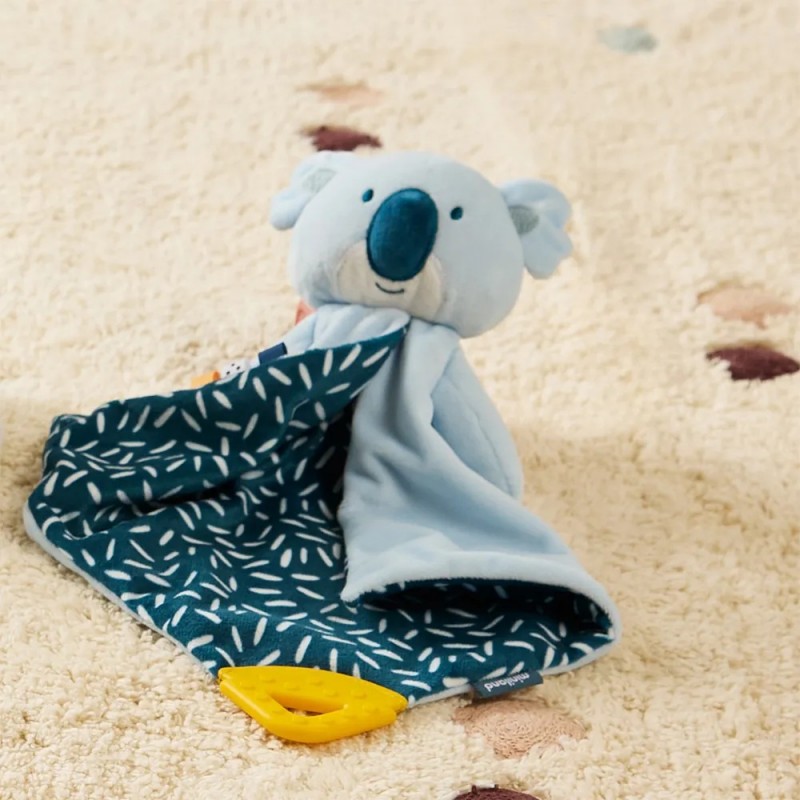 Brinquedo de peluche coala azul claro com manta azul escura com padrão branco