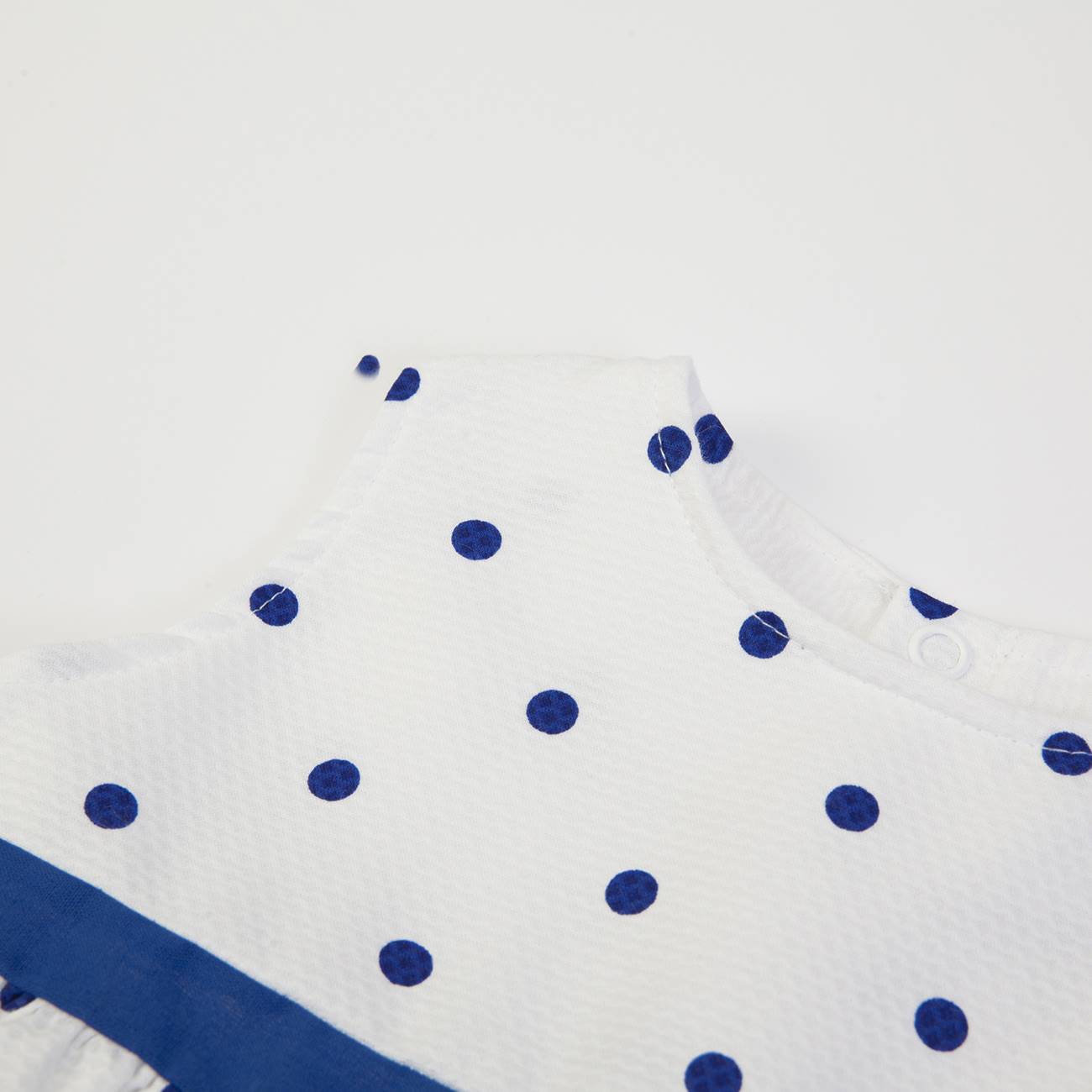 Peça de roupa branca com bolinhas azuis e faixa azul escura