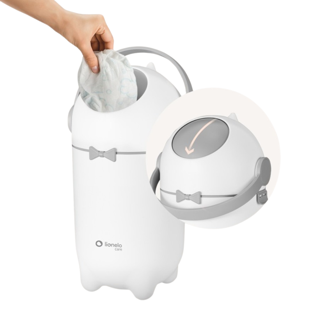Recipiente branco para fraldas com tampa e pega cinzentas, mão a colocar uma fralda no interior.