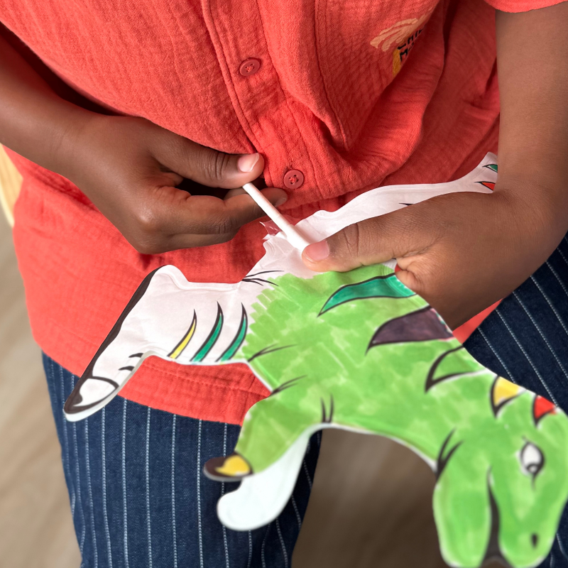 Criança com camisa laranja e calças às riscas segurando uma marioneta colorida