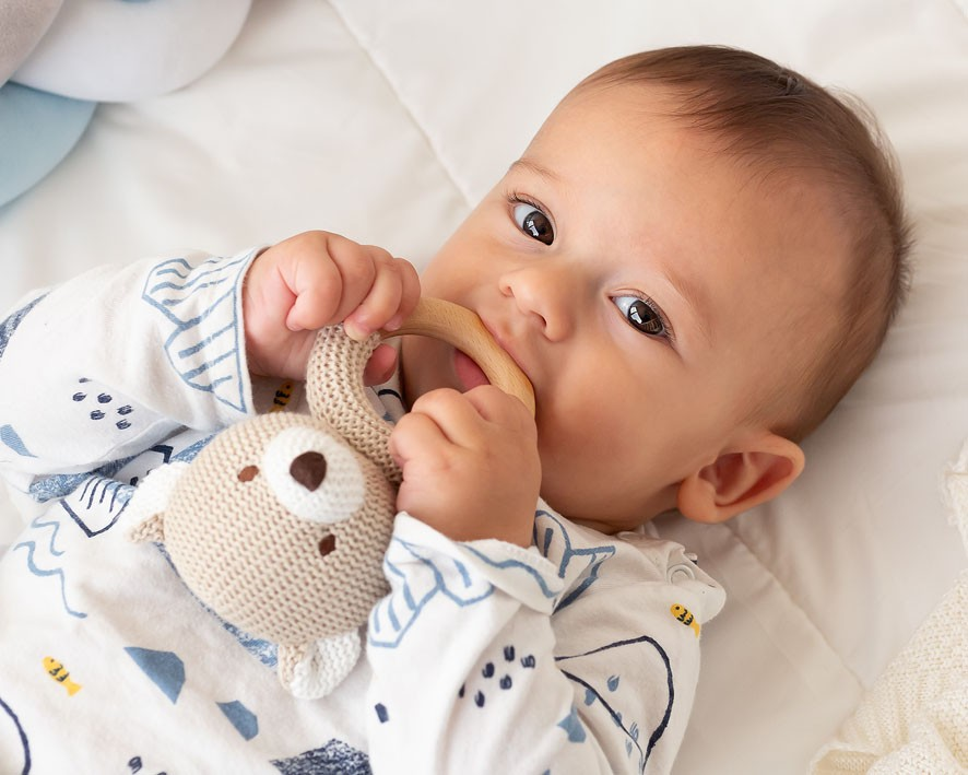 Bebé com pijama a morder brinquedo tecido em forma de coelho