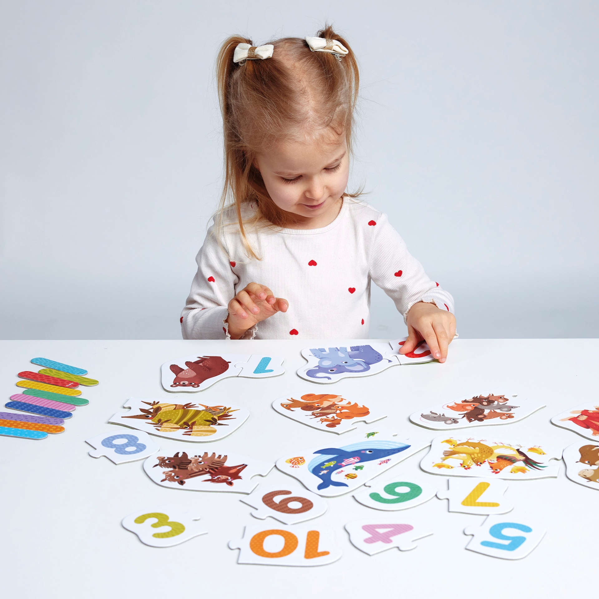 Menina a montar puzzle educativo com números e animais.