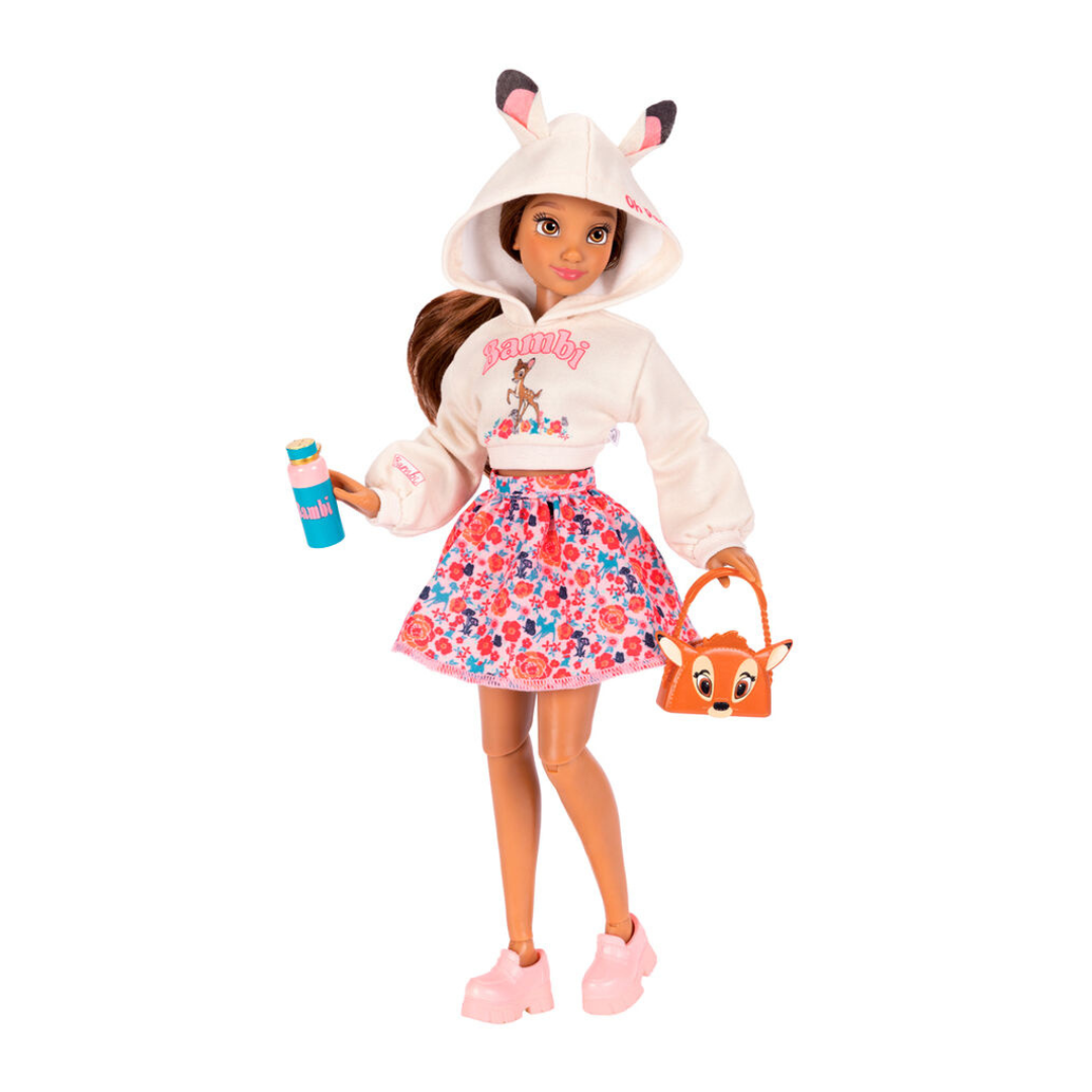 Boneca com hoodie branco, saia floral, sapatos rosa, segurando garrafa e mala com rosto de veado.