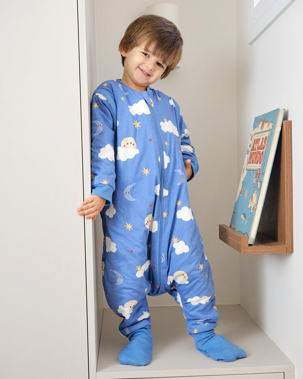 Macacão azul com padrão de nuvens, luas e estrelas visto numa criança sorridente