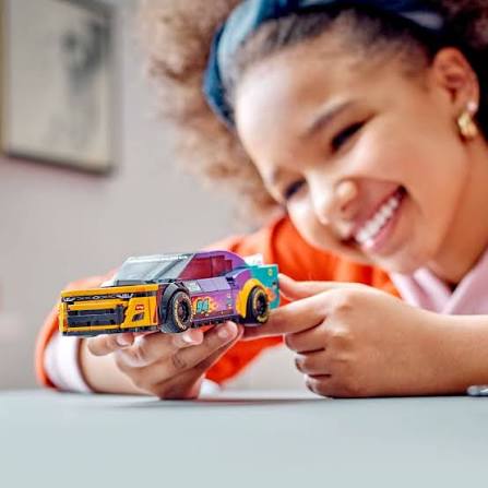 Menina a brincar com carrinho de brinquedo colorido na mesa