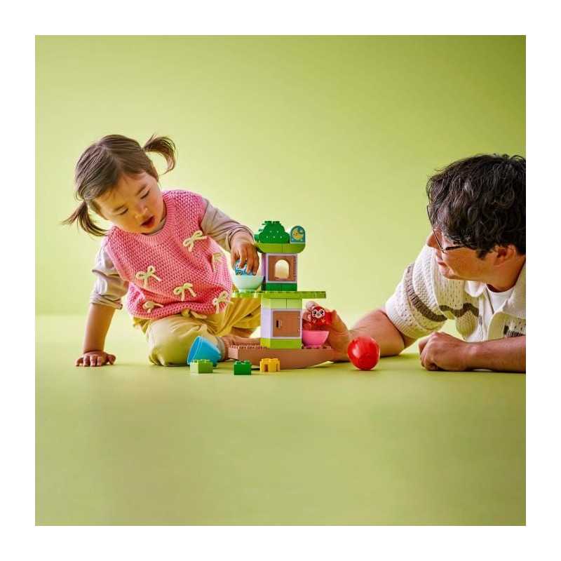 Criança e homem brincam com brinquedo de construção colorido no chão verde claro.