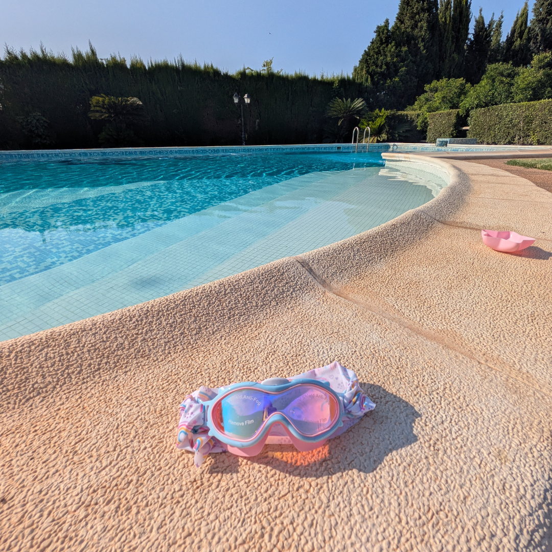 Óculos de proteção cor-de-rosa com lentes azuis na borda de piscina
