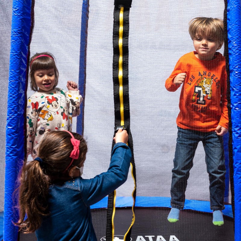 Três crianças a brincar num trampolim infantil com rede azul e preta