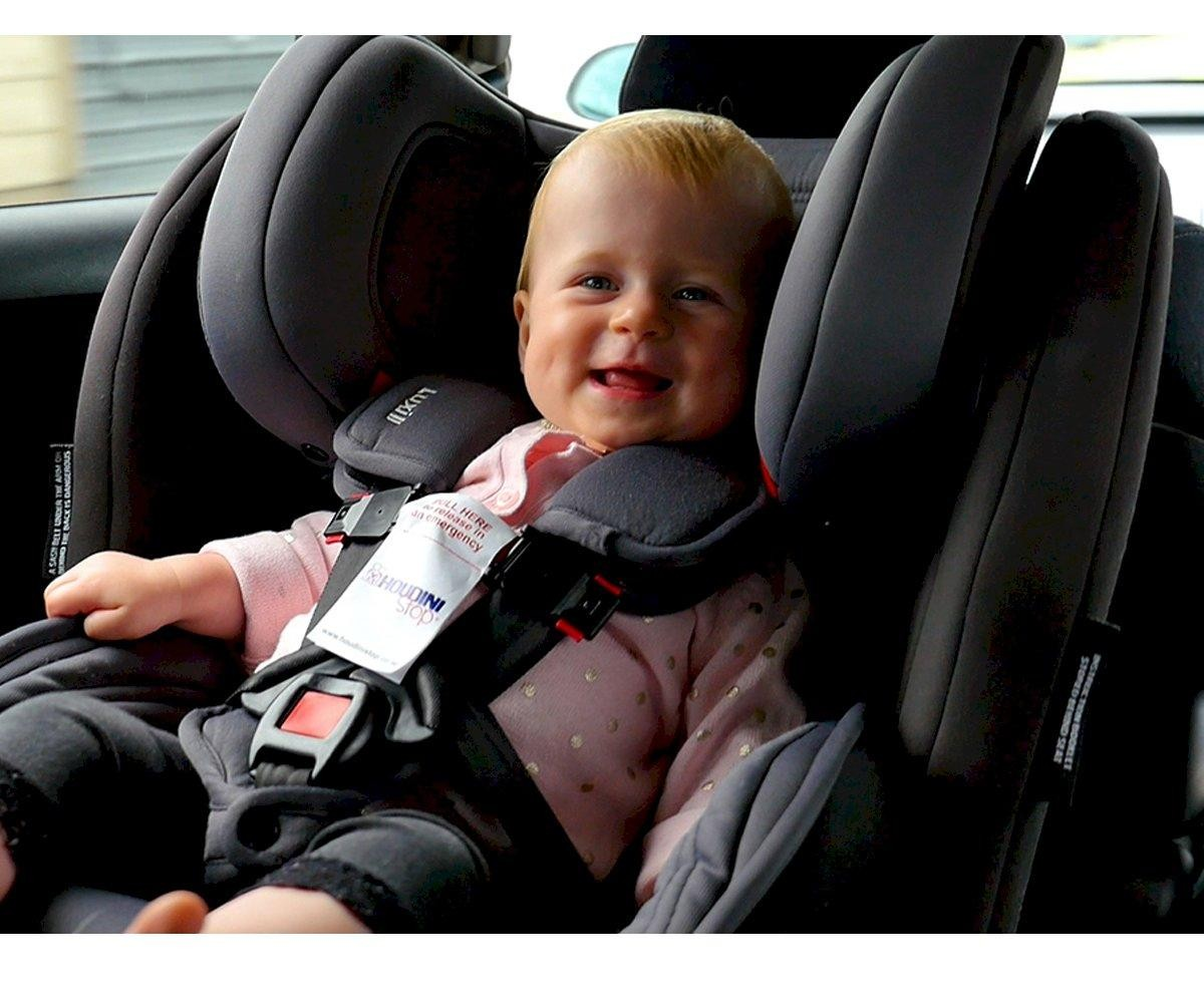 Bebé numa cadeira de carro cinza escuro com cinto de segurança e almofadas acolchoadas