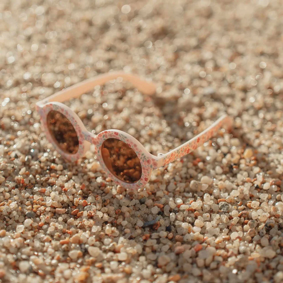 Óculos de sol infantis redondos com padrão floral na praia