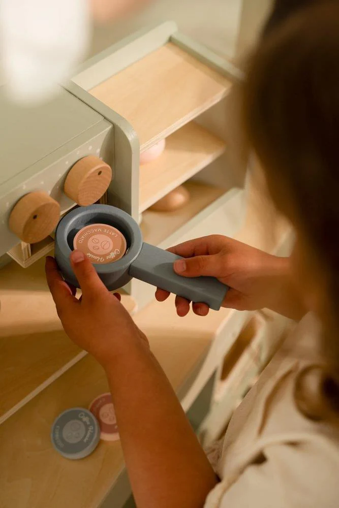 Brinquedo de cozinha em madeira com botões e discos coloridos nas mãos de uma criança