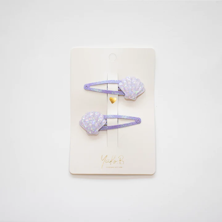 Par de ganchos para cabelo lilás com conchas peroladas em cartão branco