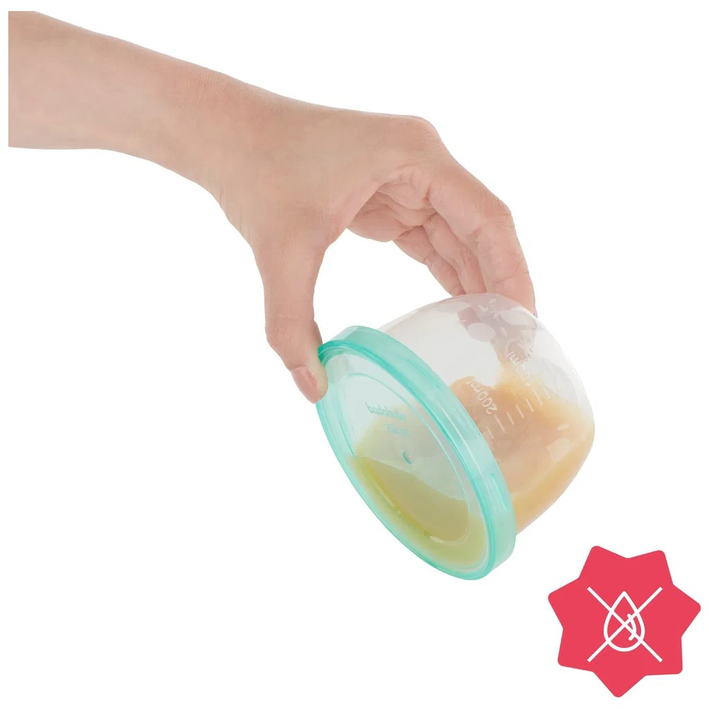 Mão segurando copo transparente com tampa verde contendo comida líquida amarela