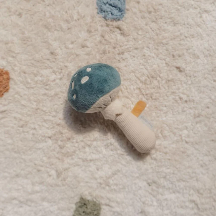 Brinquedo macio em forma de cogumelo azul sobre tapete claro