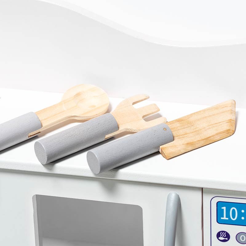 Utensílios de cozinha de madeira com cabos cinzentos numa bancada branca junto a móvel branco com painel digital