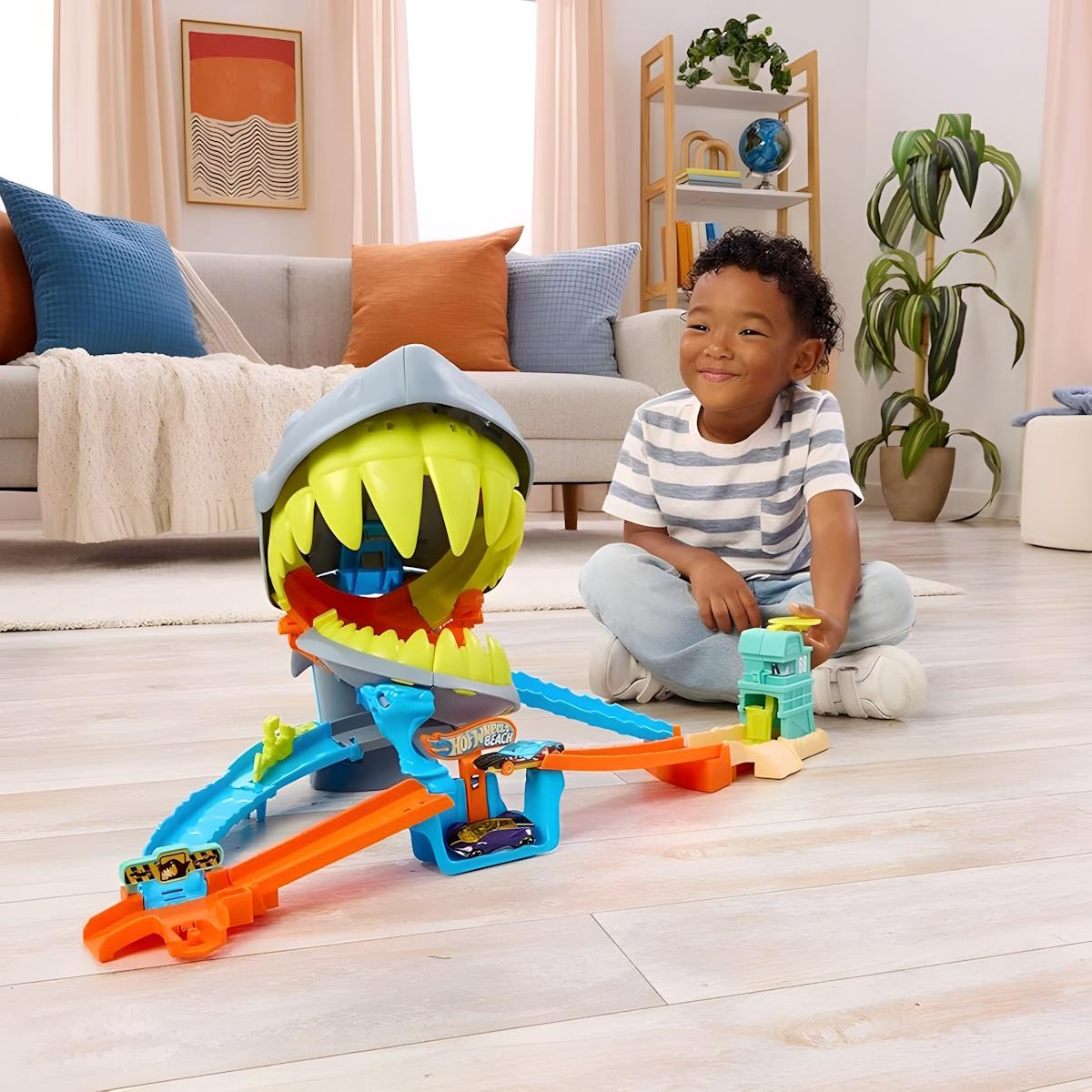 Brinquedo pista de carros tubarão colorido com menino sentado no chão em sala moderna