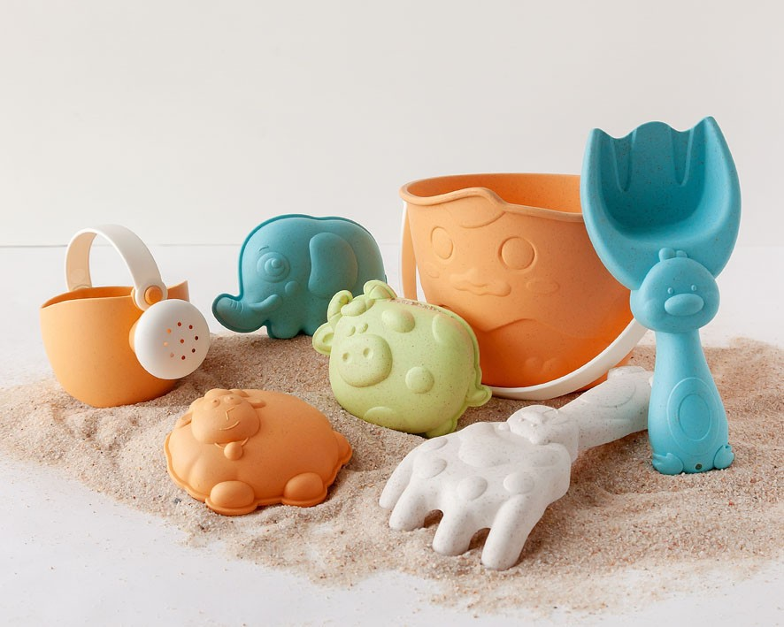 Conjunto de brinquedos de areia coloridos para crianças sobre areia e fundo branco