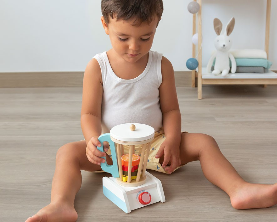 Criança a brincar com liquidificador de brinquedo em madeira colorida