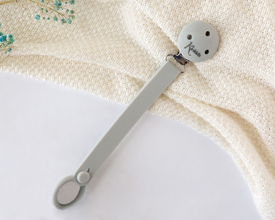 Paleta de silicone cinza claro com botão redondo sobre tecido bege e flores azuis