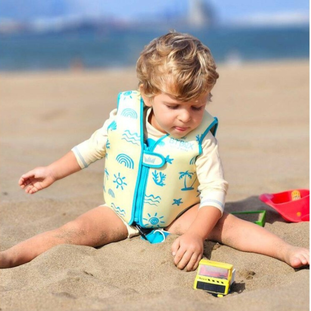 Criança na praia com colete salva-vidas amarelo e brinquedo