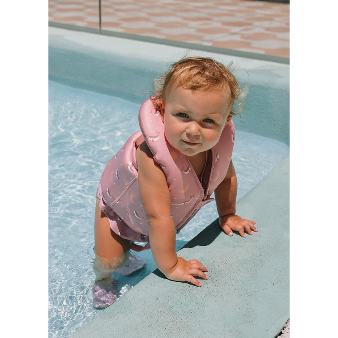 Criança com colete salva-vidas rosa na piscina