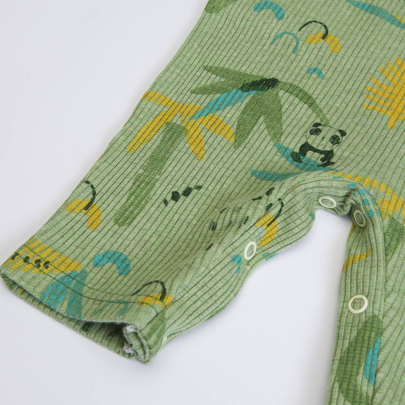 Detalhe de tecido verde com padrões de folhas e fechos de pressão brancos