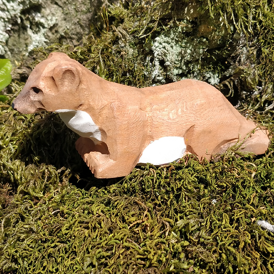 Figura de madeira de animal castanho e branco sobre musgo