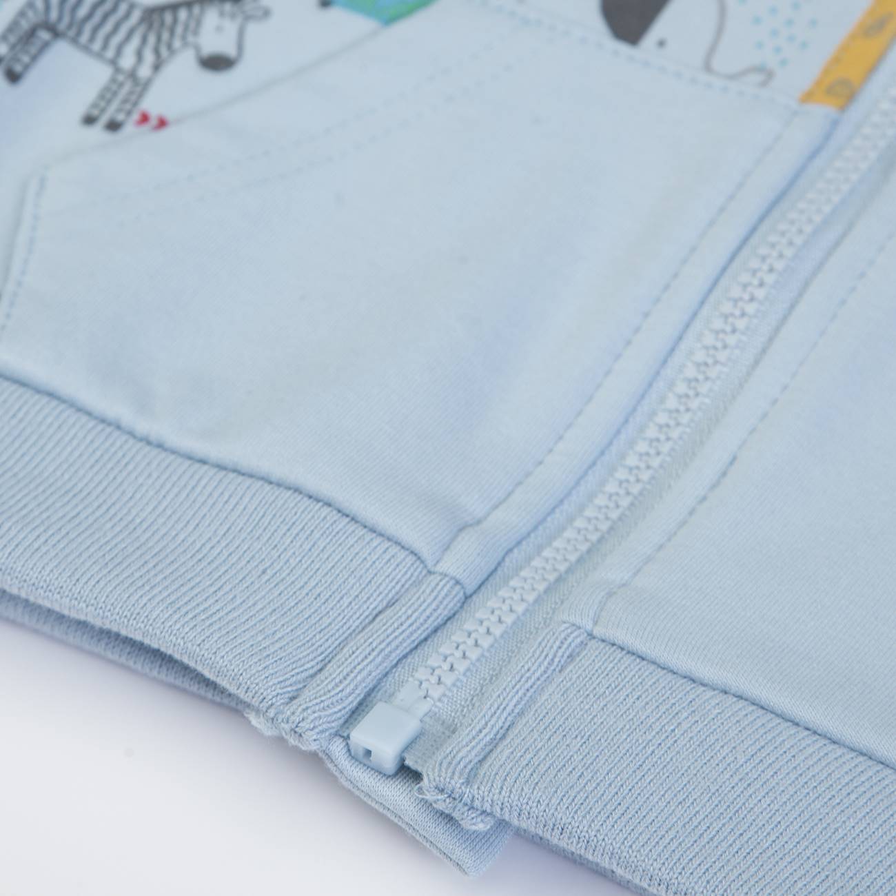 Peça de roupa azul claro com fecho de correr e costura visível.