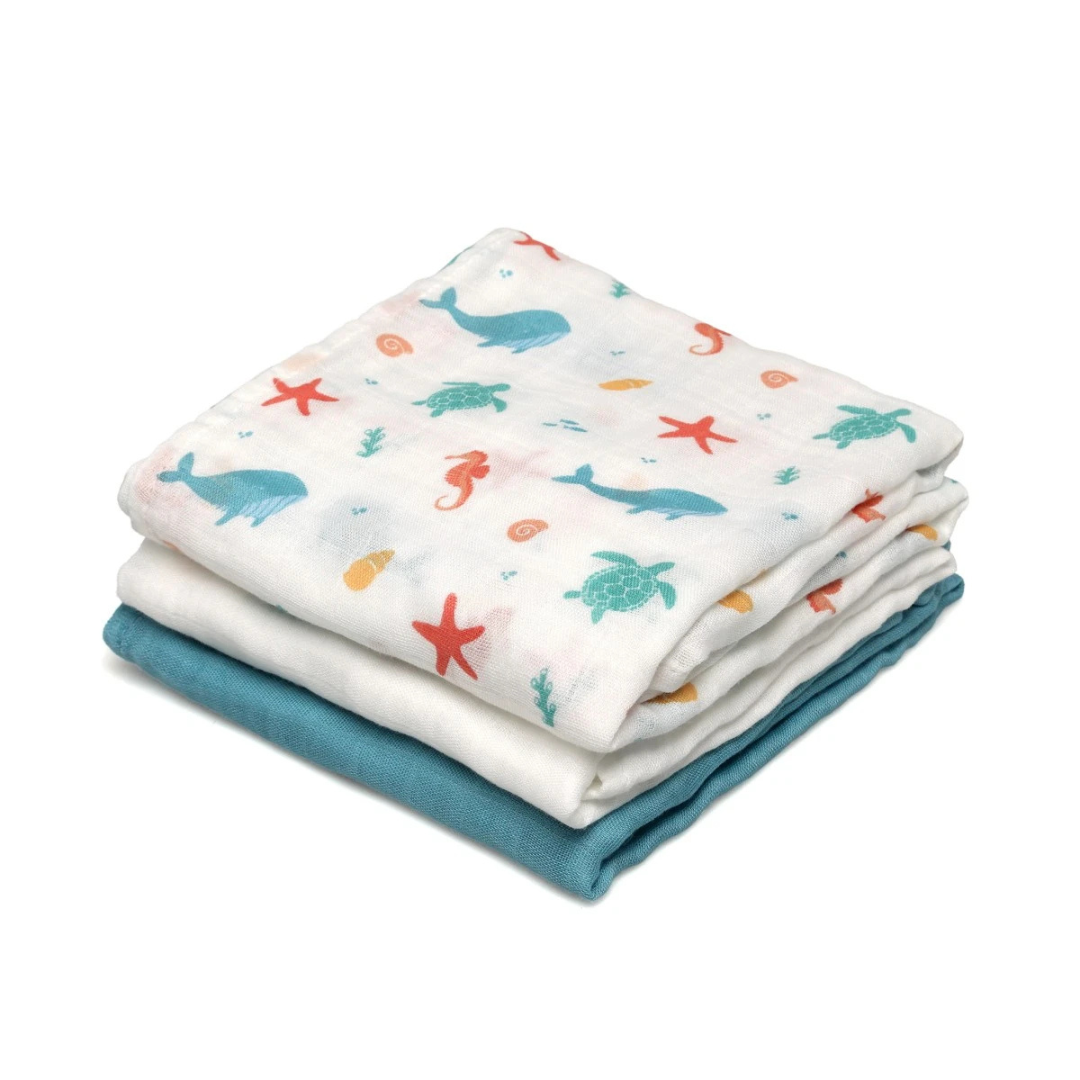 Três panos de tecido dobrados, com padrão marinho colorido, branco liso e azul-turquesa.