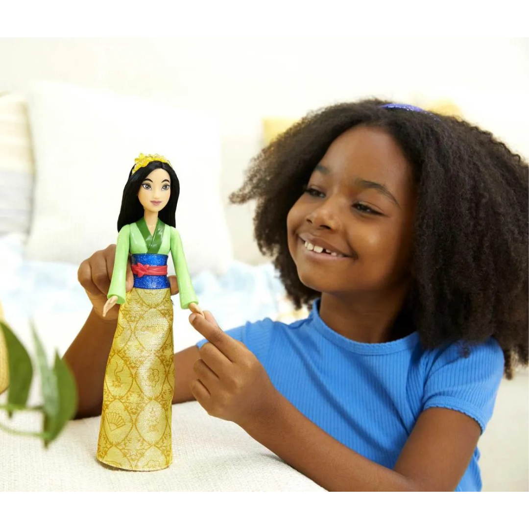 Boneca da personagem Mulan com vestido tradicional amarela e criança sorridente com camisola azul