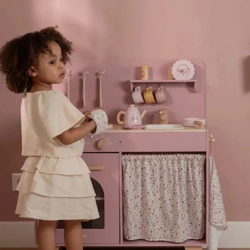 Cozinha de brinquedo rosa com acessórios e menina com vestido creme e luva floral