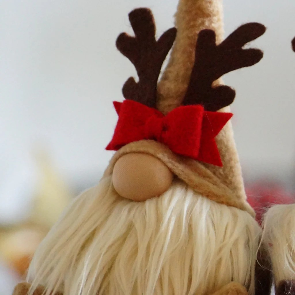 Boneco decorativo natalício com barba branca e chapéu castanho claro com laço vermelho