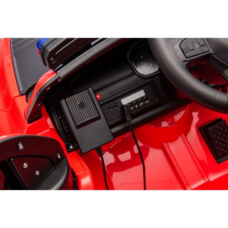 Interior de carro de brinquedo vermelho com volante preto e painel com entrada USB e controlo remoto