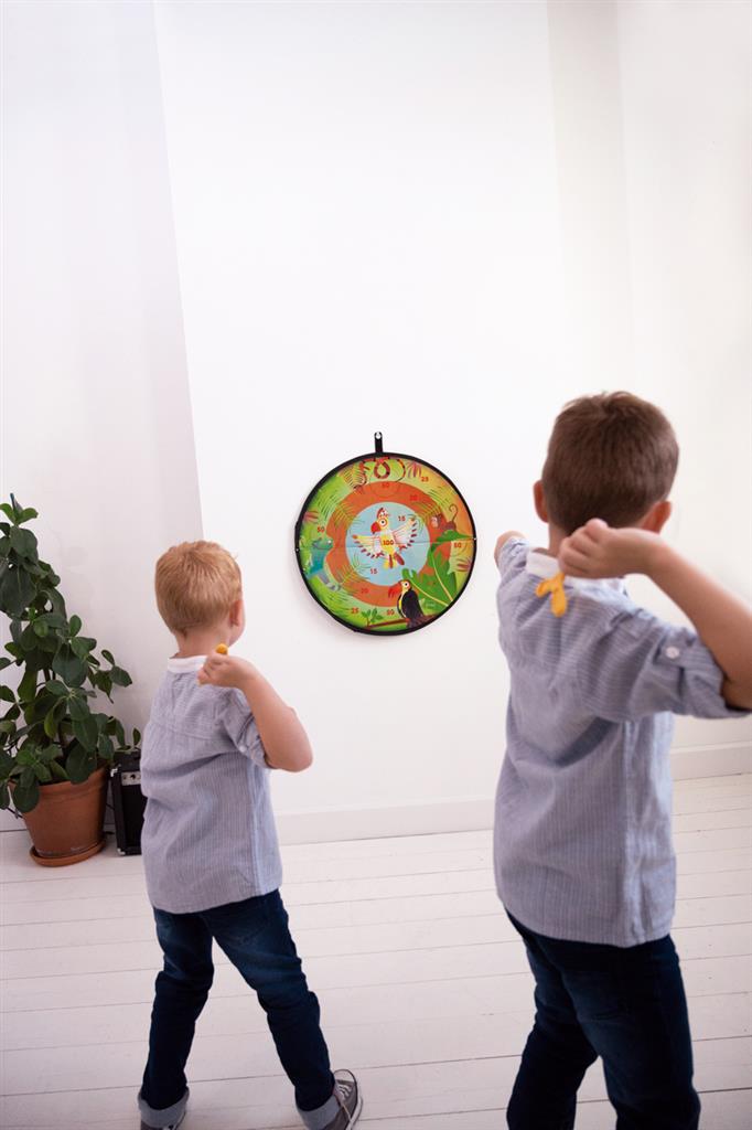 Dois rapazes a jogar dardos a um alvo colorido numa parede branca.